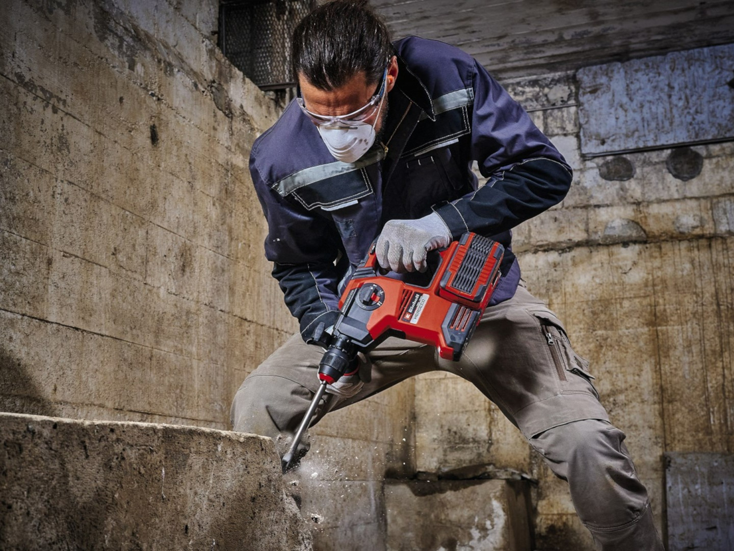 A man chisels off concrete with an impact drill