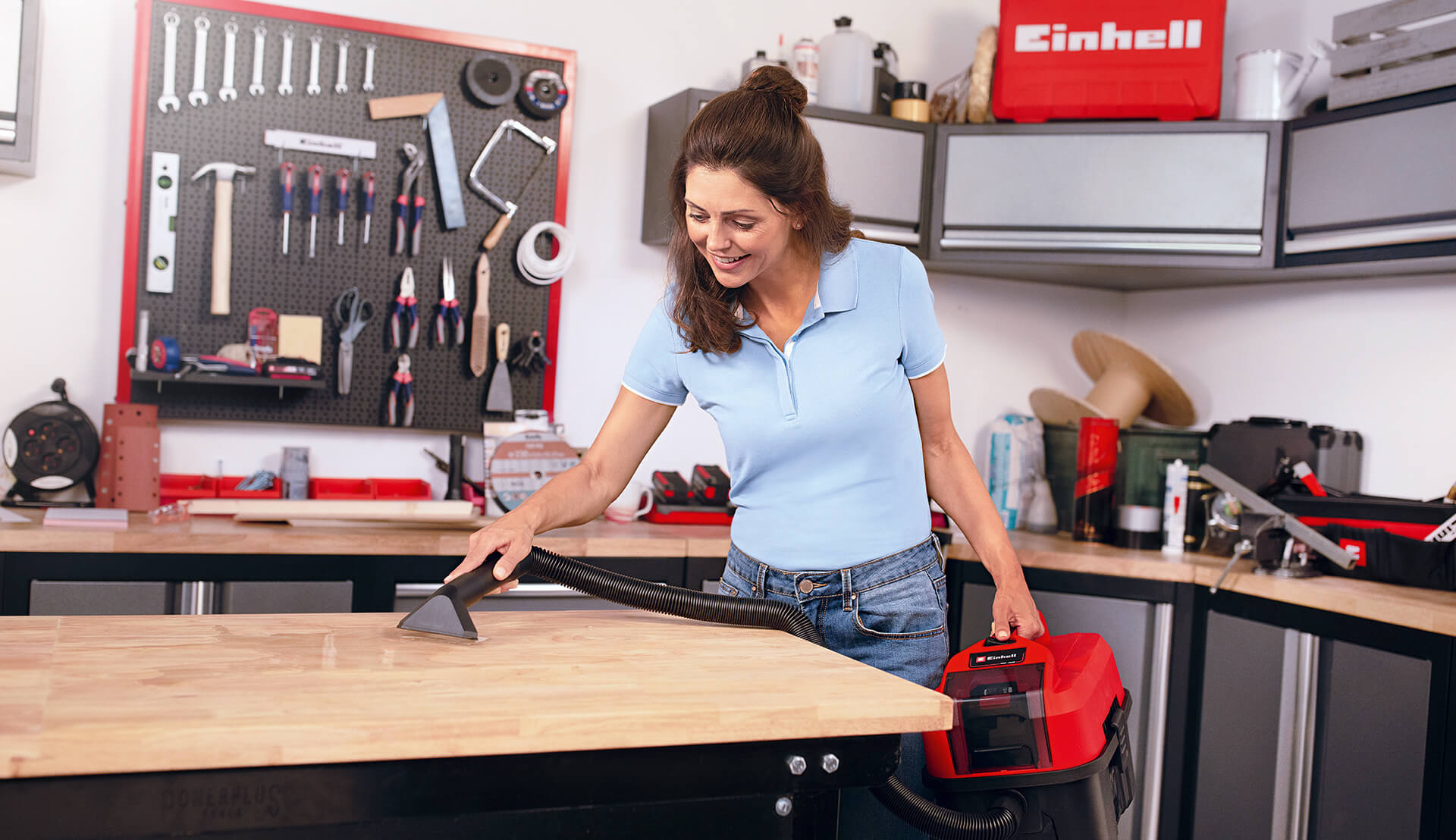 Woman cleaning workshop with wet / dry vacuum cleaner