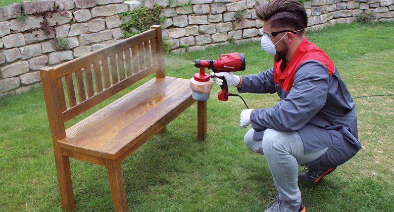 man using a paint spray gun on a bank