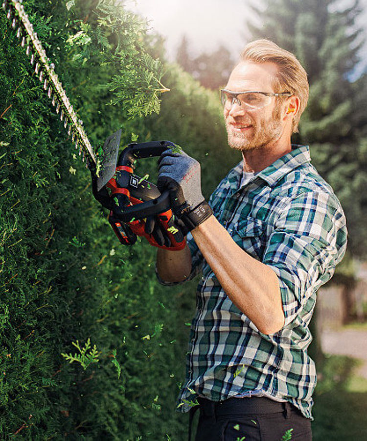 man trimming the hedge with a cordless hedge trimmer